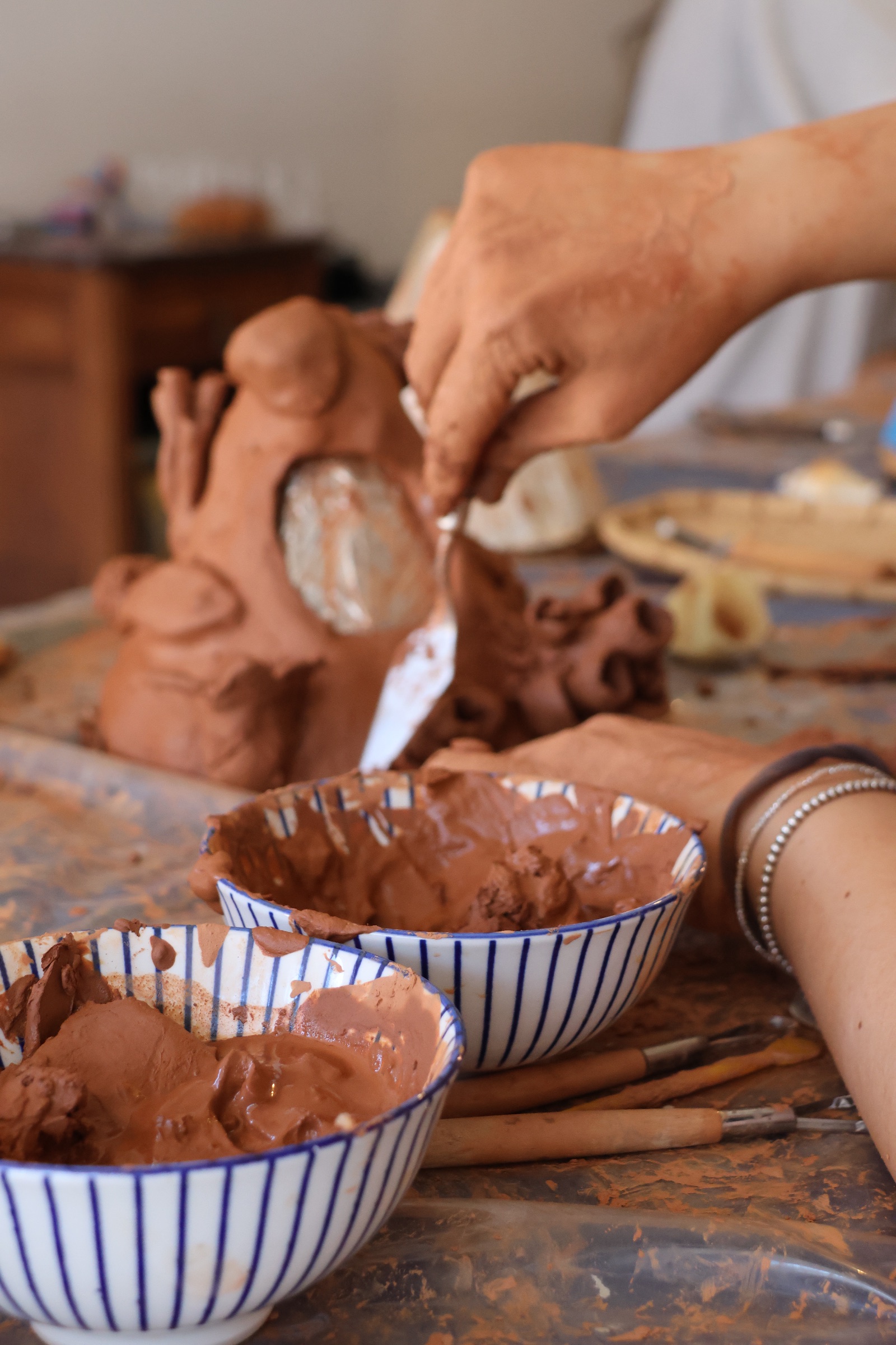 Hands sculpting a ceramic reef structure in a workshop