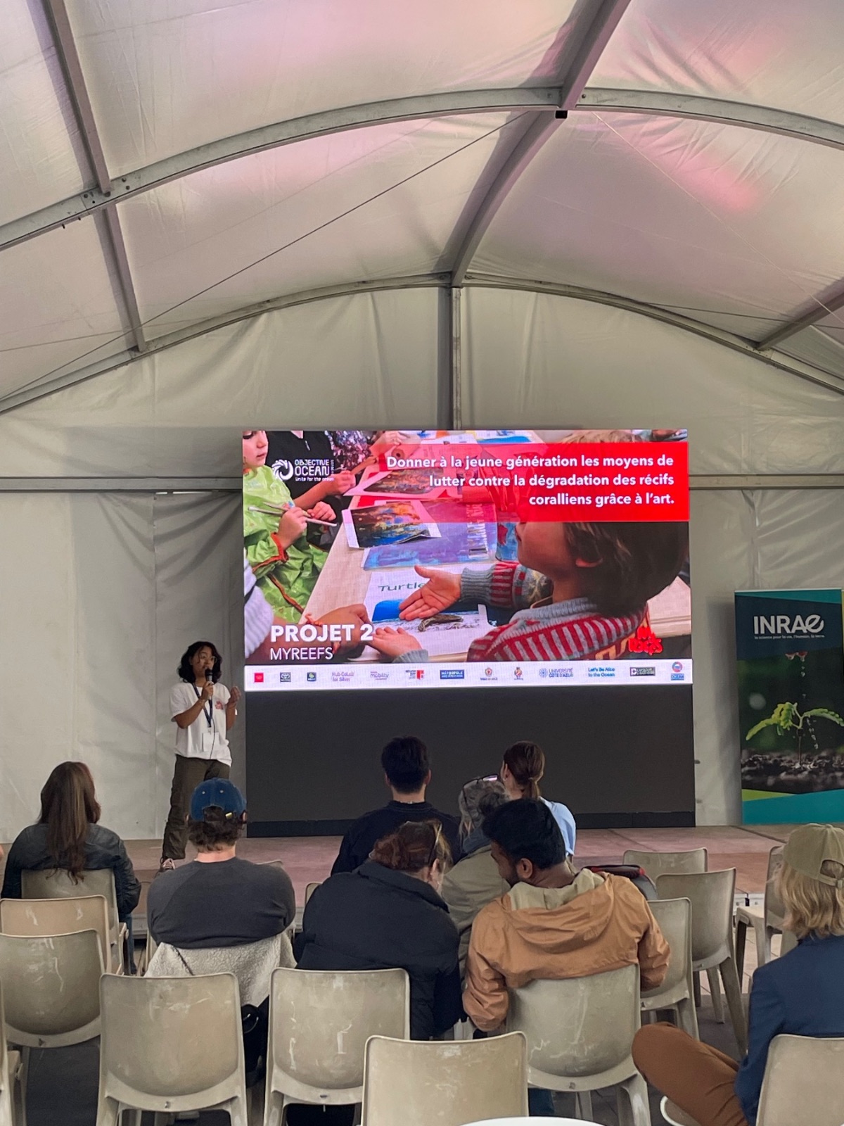 Two MyReefs founders presenting their project on stage
